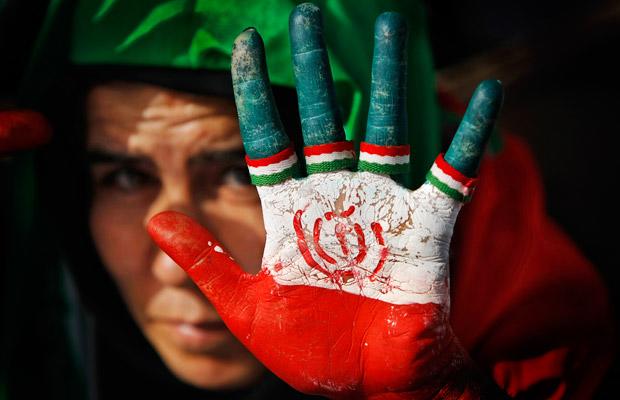 A female supporter of Iranian President Mahmoud Ahmadinejad displays her hand painted with the Iranian flag, also used as a sign for his party (Photo: AP)