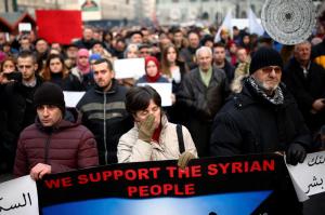 A woman, holding a placard reading "We support the Syrian people", cries as she stands among other Bosnians during a protest in Sarajevo